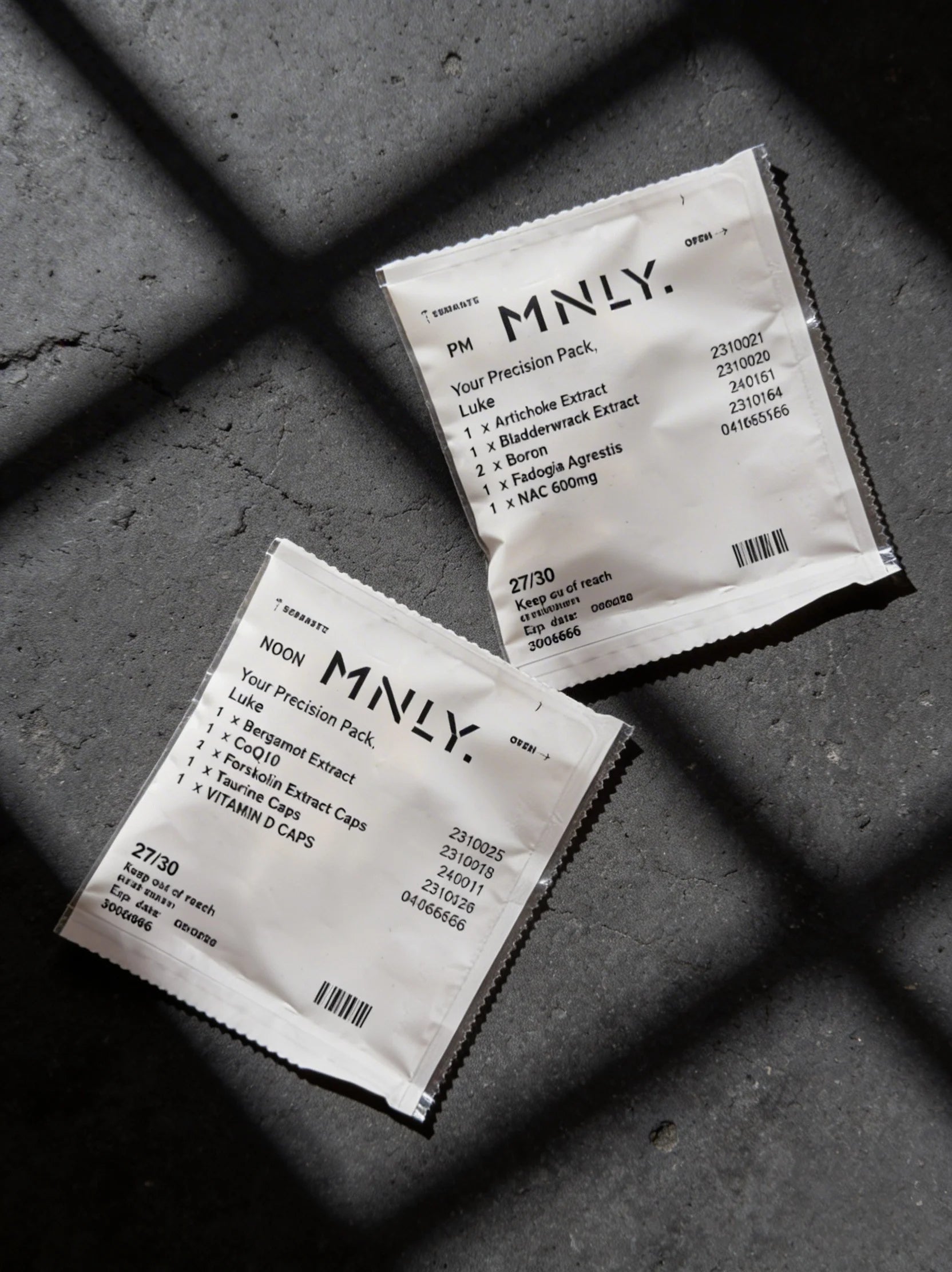 Two MNLY Precision Pack sachets on concrete
